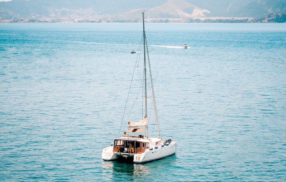 A sailing catamaran lying at anchor in a sheltered bay